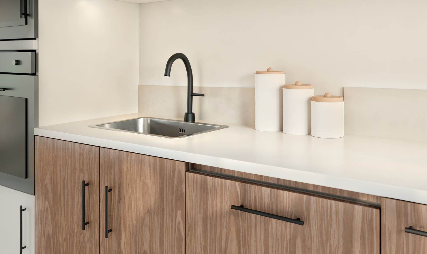 Close-up of a stainless sink and black tap on a pale worktop over walnut fronts